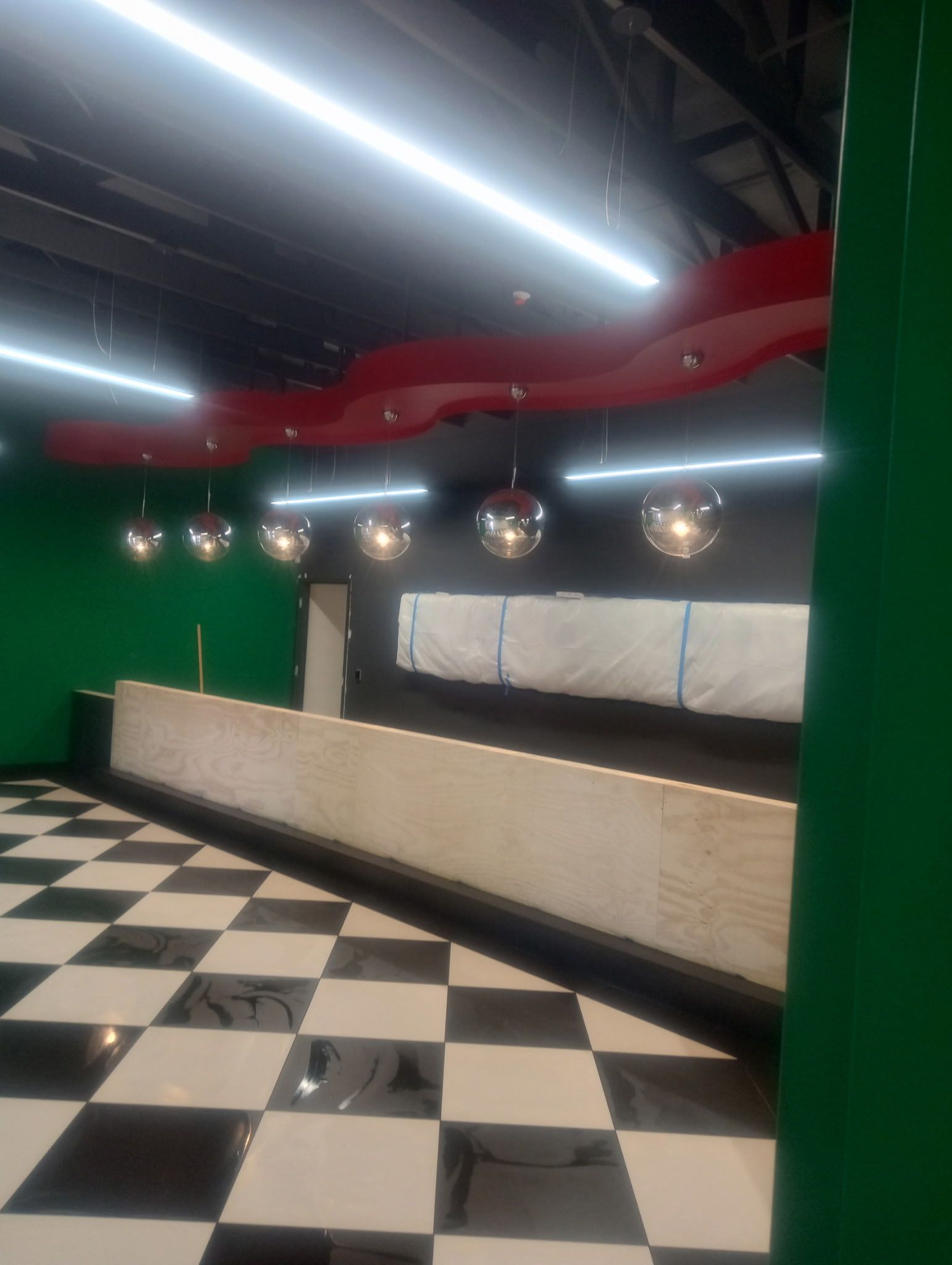 Commercial space with a black and ivory checkerboard floor, dark walls, and pendant lighting