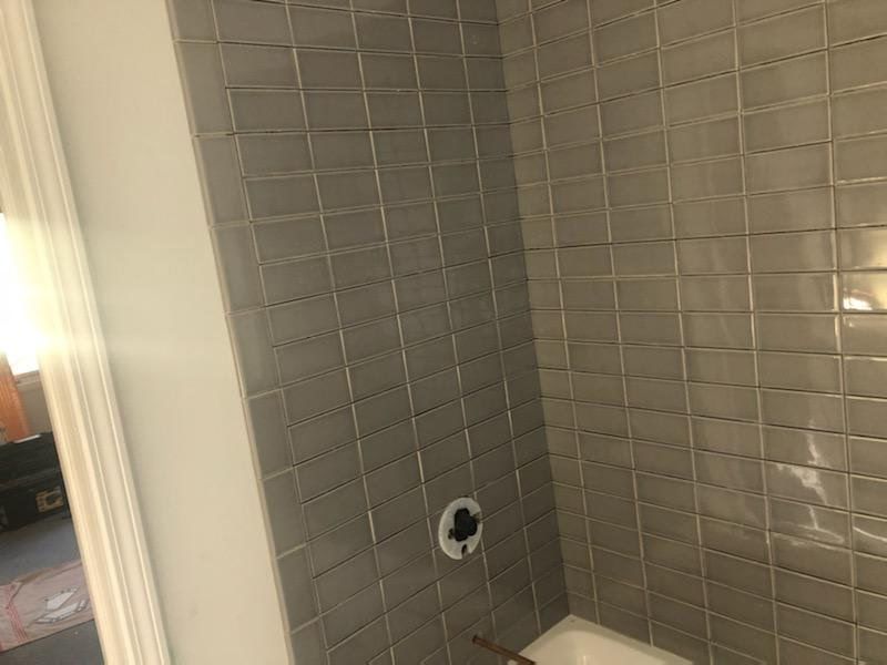 Glossy gray subway tile installation wrapping around a bathroom corner